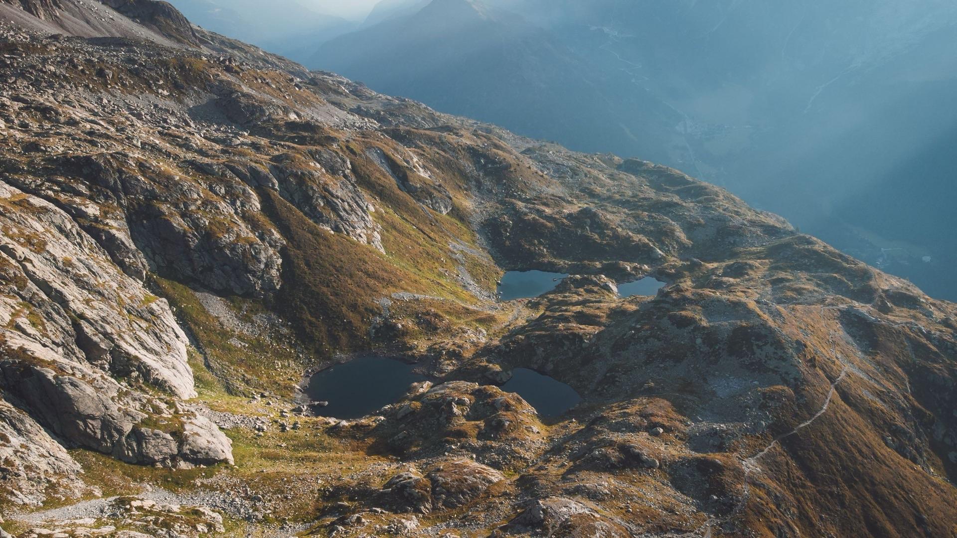 Small lakes on a rocky mountainside, seen from above in low light.