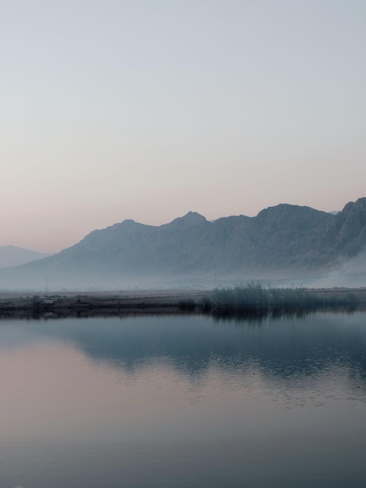 A still lake at dusk, a mountain ridge mirrored in the water.