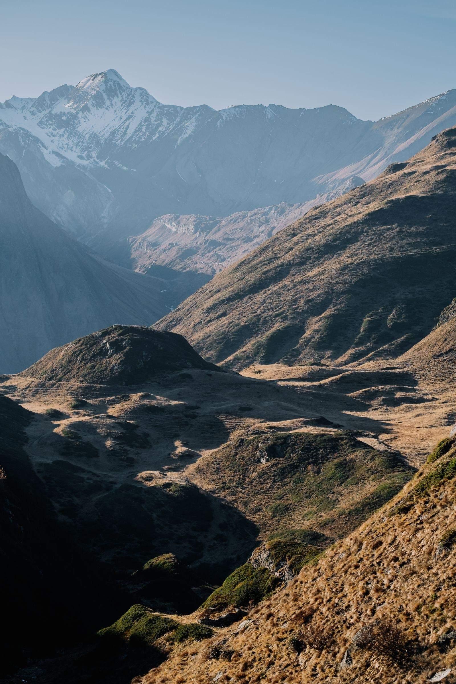 A snow-covered massif across a sunlit alpine valley, the near slopes in shadow.